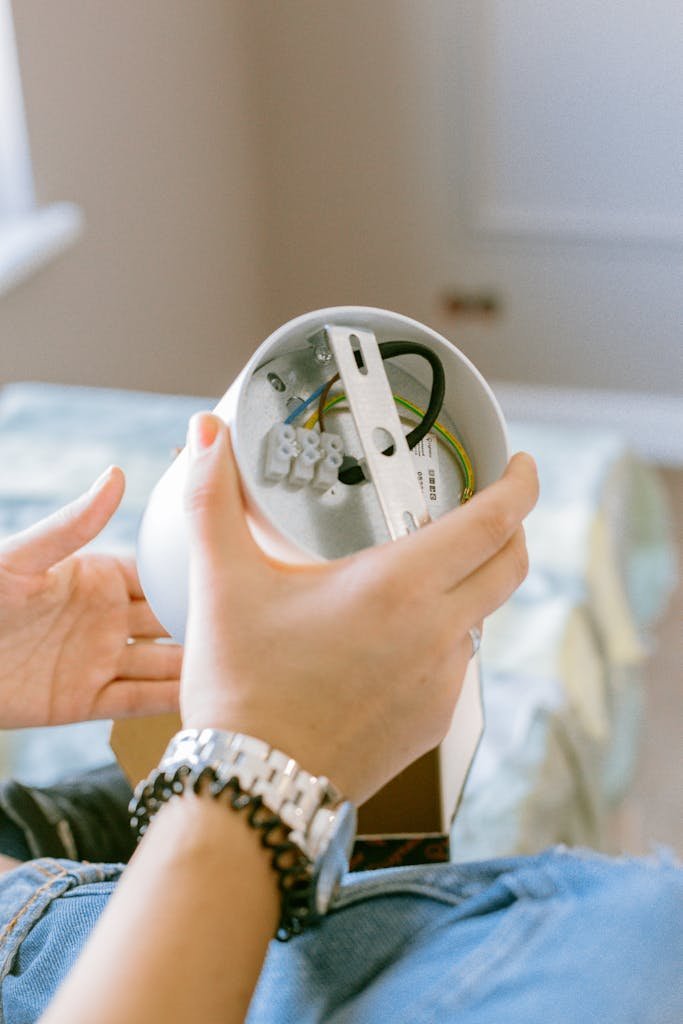 Close-up of a woman assembling a light fixture, showcasing home improvement and DIY skills.